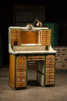 an old fashioned desk with drawers and a lamp