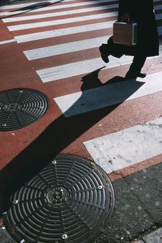 a man walking across a cross walk holding a briefcase