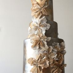 a three tiered cake with flowers on the top and bottom layer is white, gray and gold