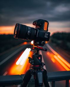 a camera is on top of a tripod with lights in the distance behind it