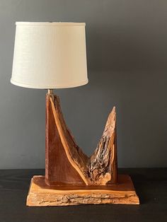 a lamp made out of wood with a white shade on it's head and neck