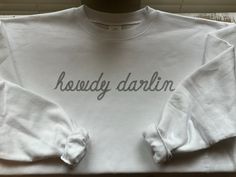 Cozy up in our Howdy Darlin Crewneck! This crewneck is the perfect gift for family, friends, and for yourself! The Howdy Darlin Crewneck design is printed on the front of the shirt only, and is available in white or ash! Our Ash color is similar to a light grey/heather grey. SIZING: Sizes S-3X are available. Please see our product photos for our measurement chart. MATERIAL: A 50% polyester / 50% cotton blend of pure comfort and softness! Shop through our "Crewnecks" section to browse our everyday styles! Stay Connected with Simply L.A. Designs: INSTAGRAM: @simplyladesigns FACEBOOK: @simplyladesigns PINTEREST: @simplyladesigns White Letter Print Sweatshirt For All Genders, Unisex White Letter Print Sweatshirt, Unisex White Sweatshirt With Letter Print, Country Crewneck Sweatshirt, Western Crew Neck Sweatshirt Pink, Western Graphic Crewneck, Western Graphic Sweatshirt, Sweatshirt Western, Western Sweatshirts