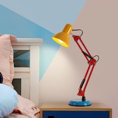 a red and yellow desk lamp on top of a blue nightstand next to a bed