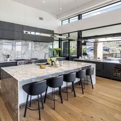 a large kitchen with marble counter tops and black chairs in front of an open floor plan