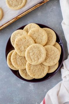 a black plate filled with cookies on top of a gray table next to a white towel