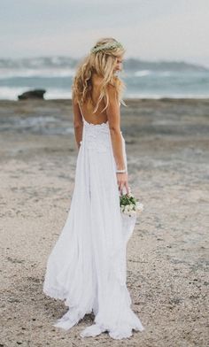 a woman standing on top of a beach next to the ocean wearing a white dress