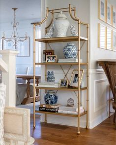 a shelf with vases and pictures on it in the corner of a living room