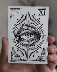 a hand holding up a card with an eye in the middle and buildings around it