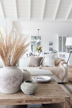 a living room filled with furniture and a large white vase on top of a wooden table