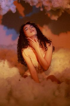 a woman is standing in the clouds with her hands on her chest and eyes closed