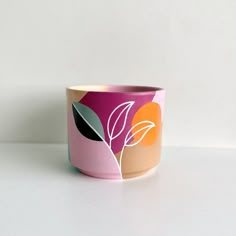 a pink and orange flower pot sitting on top of a white table