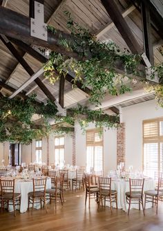 an indoor venue with tables and chairs covered in greenery