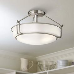 a light fixture hanging from the ceiling in a room with white walls and shelves on either side