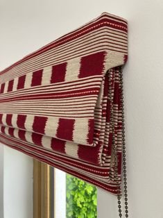 a red and white striped curtain hanging on the side of a wall next to a mirror