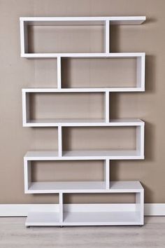 a white book shelf sitting on top of a hard wood floor next to a wall