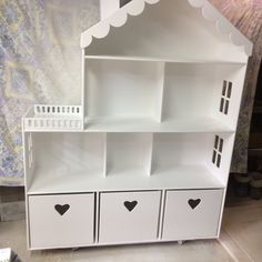 a white doll house with black hearts on the drawers