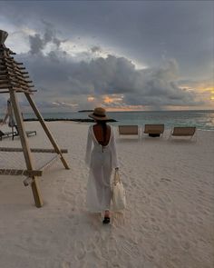 a woman is walking on the beach with her handbag