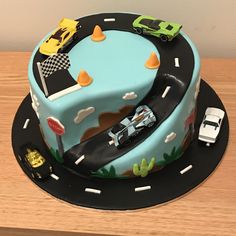 a birthday cake with cars and trucks on the top is decorated in blue icing