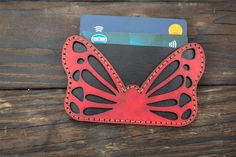 a red and black butterfly wallet sitting on top of a wooden table