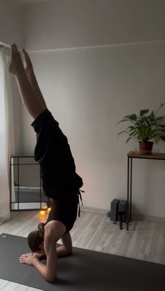 a person doing a handstand on a yoga mat in front of a window