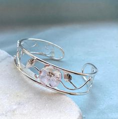 Dainty open work floral bangle, hand made in sterling silver. Wild roses and leaves curl around this pretty bracelet. Open at the back to slide on One time piece  Sturdy but with a delicate appearance  Hallmarked Bangle Silver, Silver Metal Bracelet, Whimsical Silver Flower Jewelry, Adjustable Silver Flower Bangle, Sterling Silver Flower-shaped Bracelets, Elegant Silver Flower-shaped Bracelets, Sterling Silver Flower Bracelet, Lily Bracelet, Wire Jewelry Patterns