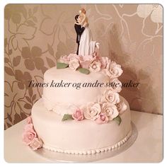 a wedding cake with pink flowers and a bride and groom figurine on top