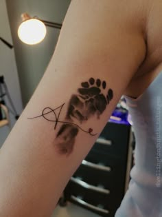 a person with a tattoo on their arm that has a dog paw and an arrow