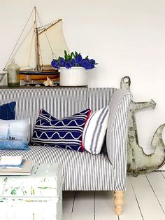 a living room filled with lots of furniture next to a wall mounted ship on the wall