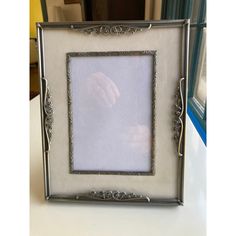 an ornate silver frame holds a baby's hand in the center, on a white table