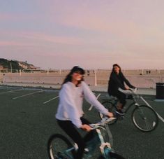 two women are riding bikes in an empty parking lot