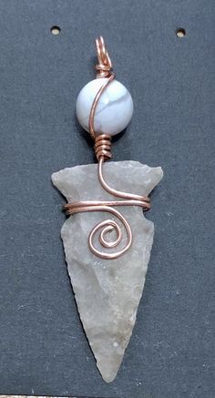 a piece of wire wrapped around a rock with a white bead on it's end