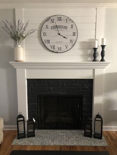 a fireplace with a clock on the wall above it and two lanterns in front of it