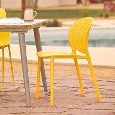 two yellow chairs sitting at a table next to a pool