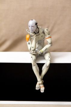 a white robot sitting on top of a black and white table next to a brown wall