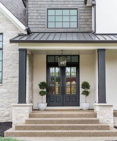 the front door of a house with two potted plants on the steps and an entry way leading up to it