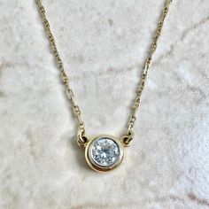 A spectacular vintage 14 karat yellow and white gold solitaire pendant necklace featuring a 5.25 mm natural round diamond weighing approximately 0.60 carat. It is G-H in color and VS2 in clarity. The necklace is 15 inches long. The bezel is 7.50 mm in diameter. The chain is 1.25 mm thick and equipped with a safety snap tab. Weighs 3.42 grams. Stamped 14K. Birthstone: April. Condition: Very good. Light scratches and wear throughout metal. - 14 day return policy, no questions asked. - Free insured Classic Solitaire Necklace With Bezel Setting, Gold Solitaire Necklace For Formal Events, White 14k Gold Solitaire Necklace, Gold Solitaire Necklace With Round Stone For Formal Occasions, Classic Round Cut Diamond Necklace With Bezel Setting, Timeless Yellow Gold Solitaire Necklace With Round Stone, Classic Solitaire Pendant Necklace With Bezel Setting, Classic Pendant Diamond Necklace With Bezel Setting, Classic Gold Solitaire Necklace