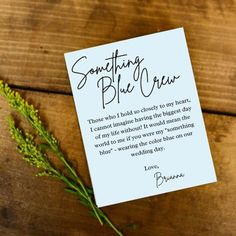 a card that says something blue new on top of a wooden table next to a plant