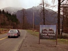 a car driving down the road past a sign that says wildwood twin peaks on it