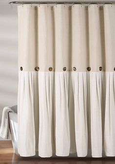 a white shower curtain with buttons on the top and bottom, in front of a bathtub