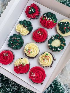 twelve decorated cupcakes in a white box on a christmas tree with red and green frosting