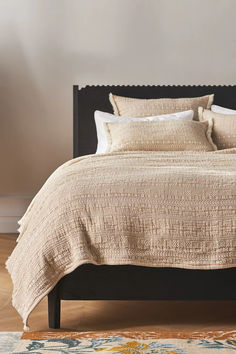 a bed with two pillows on top of it and an area rug in front of the bed