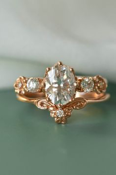 a close up view of a ring with an oval shaped diamond in the center and three smaller round diamonds on each side