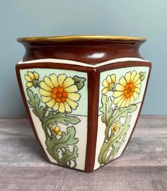 a brown vase with yellow flowers painted on it