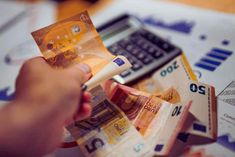 a person is counting money in front of a calculator and some other bills