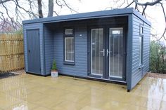 a small blue shed sitting in the middle of a yard