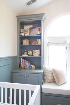 a baby's room with bookshelves, crib and window in the corner