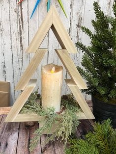 a candle sits in front of a wooden christmas tree