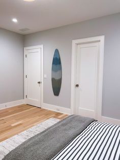 there is a surfboard hanging on the wall in this bedroom with wood flooring