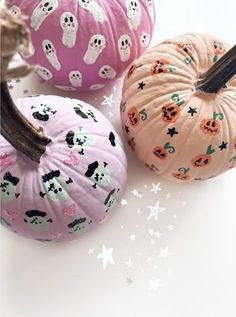 three painted pumpkins sitting on top of a white table next to stars and skulls