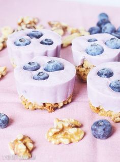 blueberry cheesecakes are arranged on a pink cloth with walnuts scattered around them